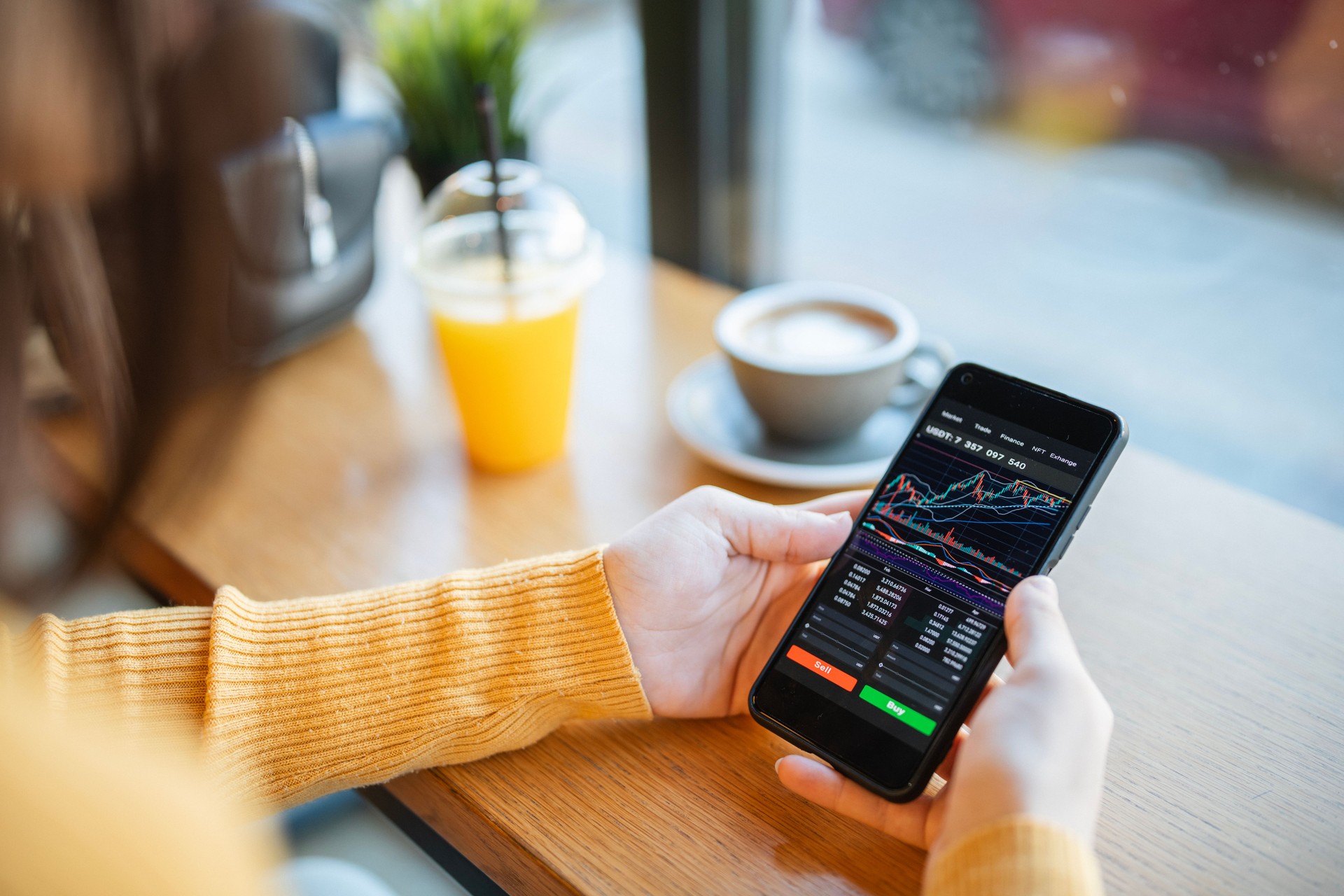 Trading with cryptocurrency on smartphone and enjoying coffee.